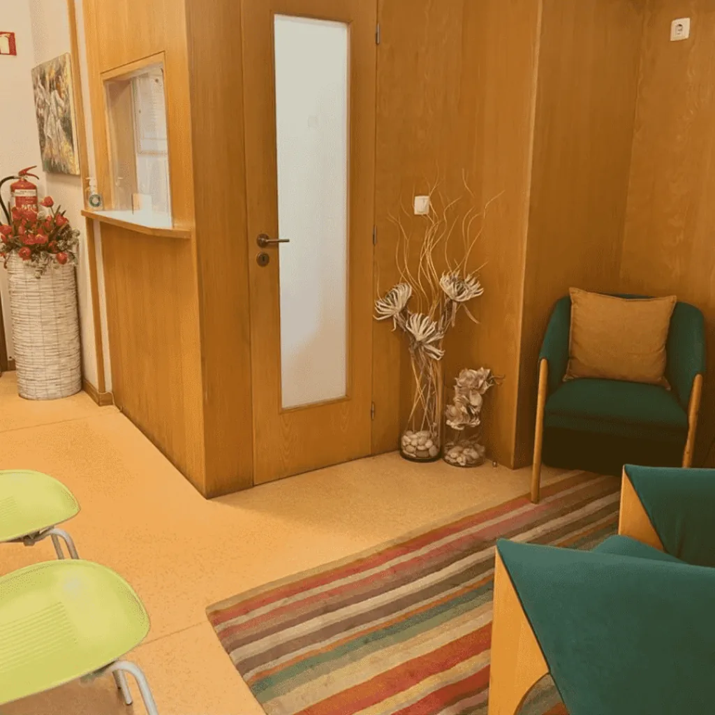 Zona de espera, com poltrona e cadeiras junto à porta dos gabinetes