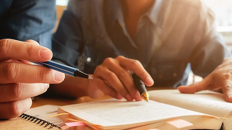 Apontamentos, marcadores e um caderno de estudo sobre a mesa