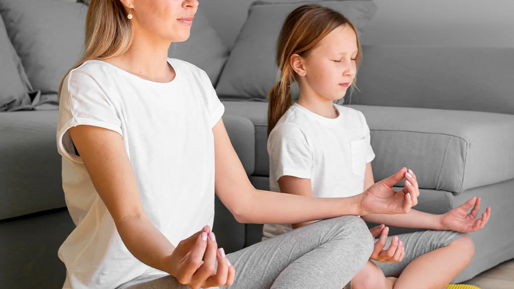 Adulto e criança sentados em posição de meditação